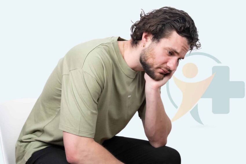 Homme triste assis, la main sur le visage, montrant sa frustration face à l'éjaculation précoce