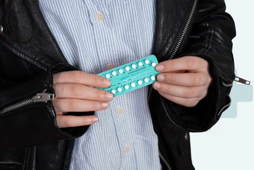 Person holding a pack of hormonal pills used for menstrual suppression treatment